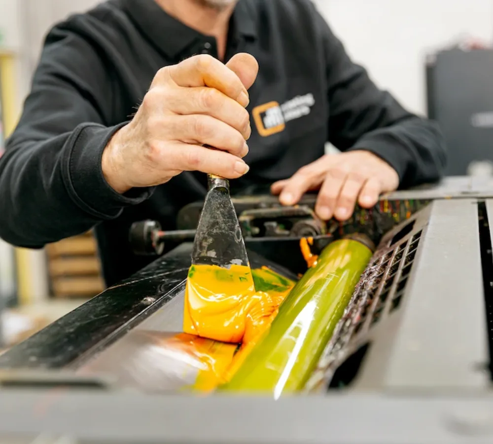 Medewerker van MarketingMakkers brengt inkt aan op drukmachine