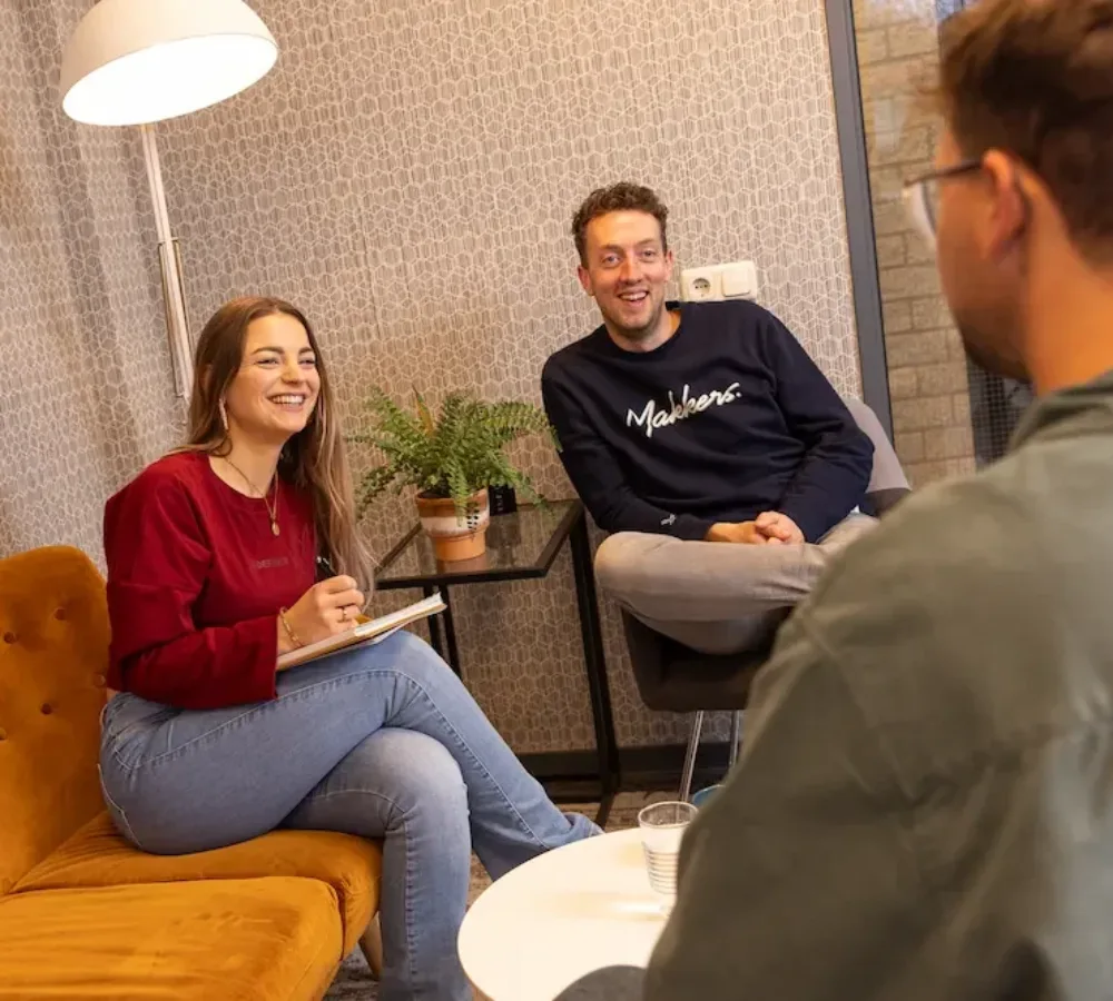 Drie medewerkers van MarketingMakkers in gesprek op kantoor