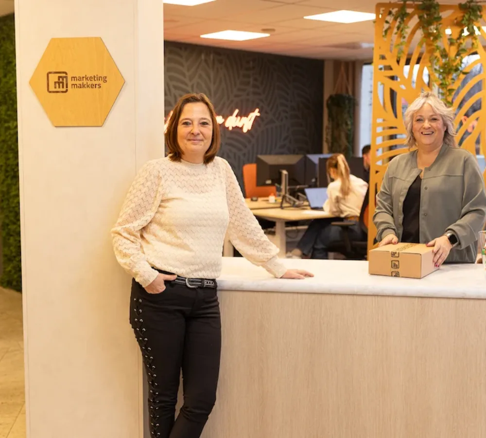 Twee medewerkers van MarketingMakkers staan bij balie op kantoor