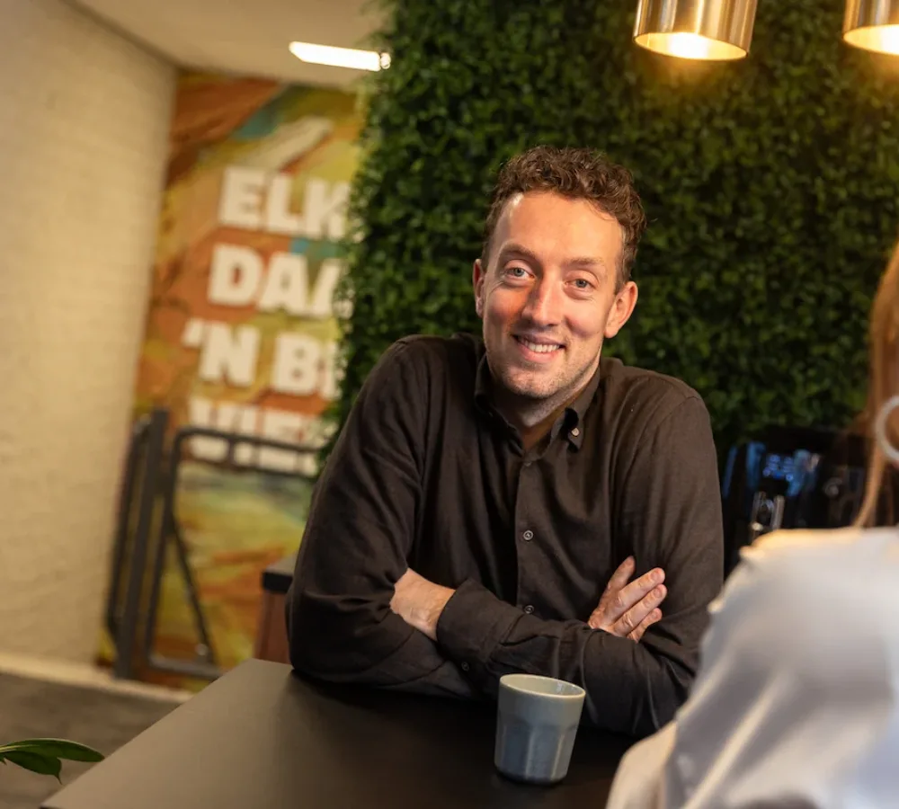 Medewerker MarketingMakkers leunt op tafel in kantooromgeving