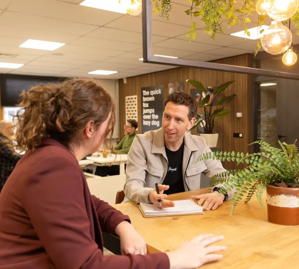 Twee medewerkers van MarketingMakkers in overleg aan tafel met notities