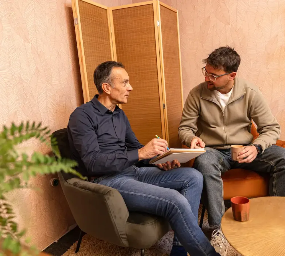 Twee medewerkers van MarketingMakkers in gesprek met laptop in kantoorruimte