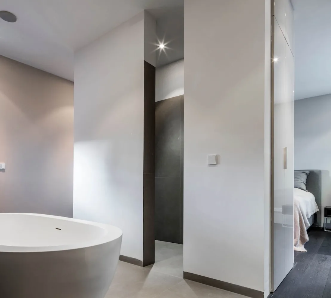 Badkamer met vrijstaand bad en strakke wandafwerking